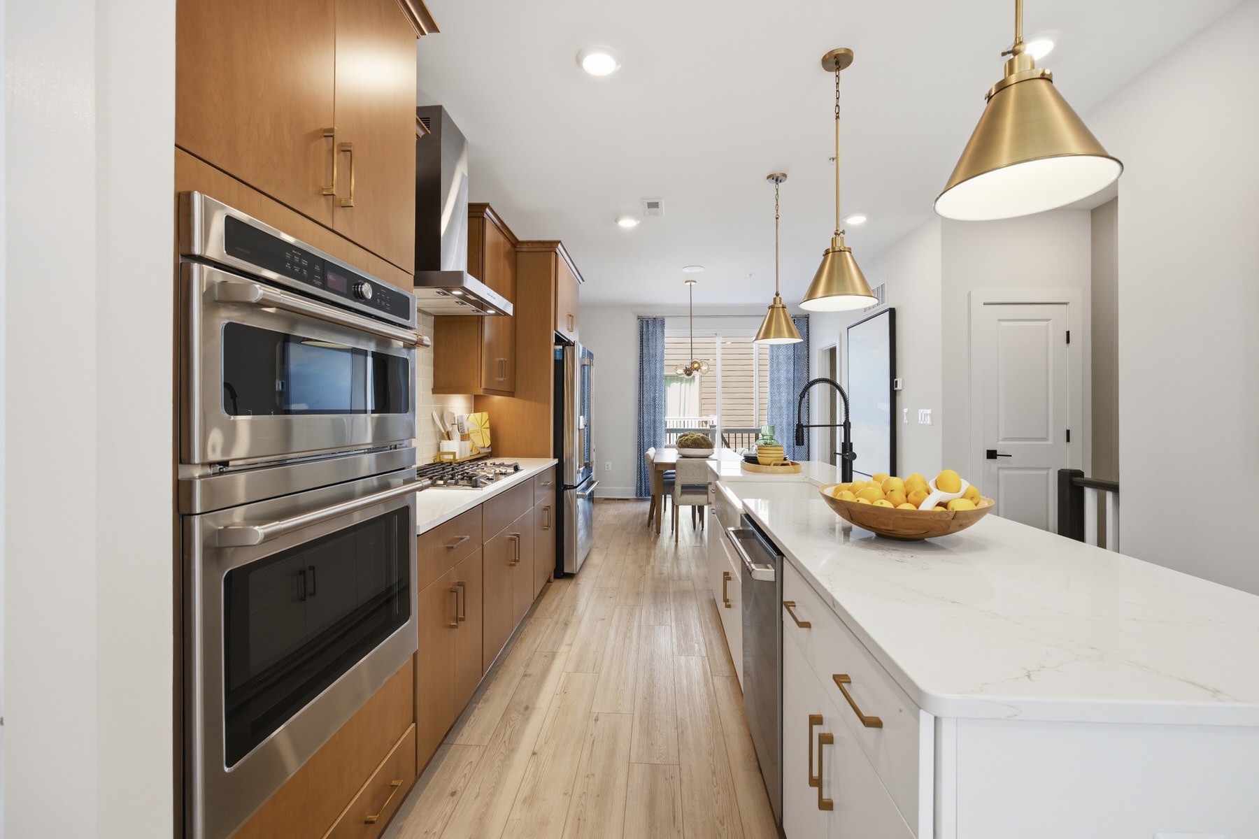 Kitchen with warm wood cabinets, gold pendant lights, and island seating, real estate photography Baltimore MD