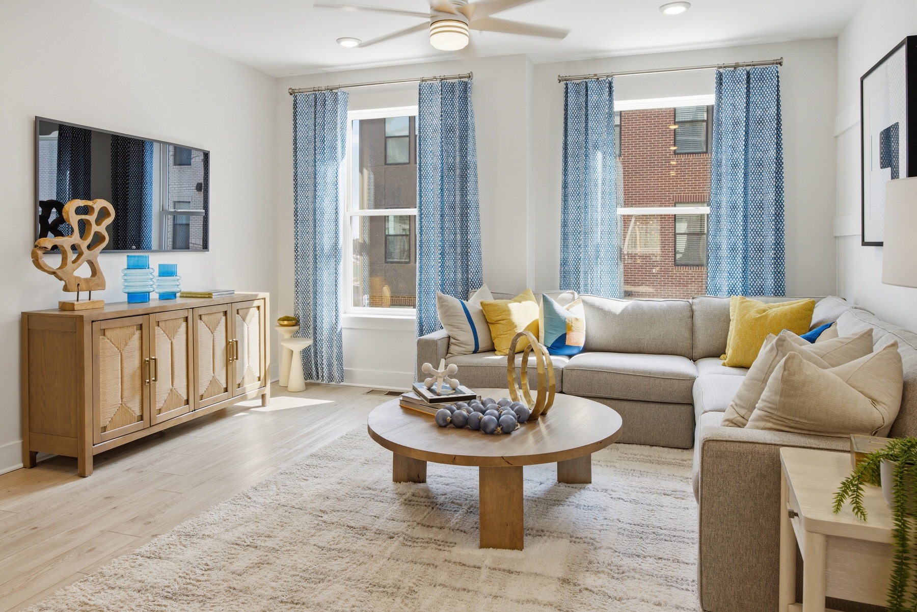 Staged living room with blue accent pillows and large windows, real estate photography Central Maryland
